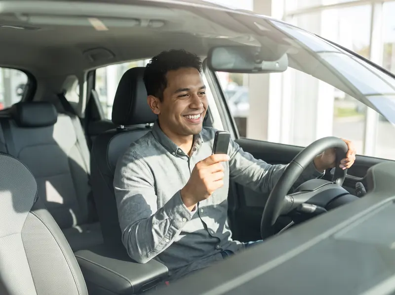 A man in the driver seat of a new car, holding the key